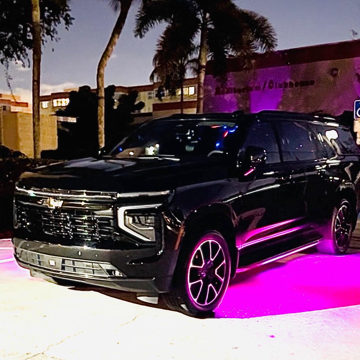 Executive black Suburban with pink underglow